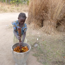 Norida pounding mpundu fruits in her family's ibende (mortar).