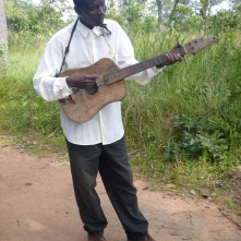 Ba Allan, trying unsuccessfully to play the bush guitar. ("Bush" because it's homemade.)