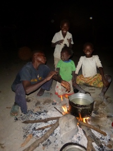 Four of the Mutale kids around their evening fire: Boyd, Gile, and Cila up front, with Joyci in the background.