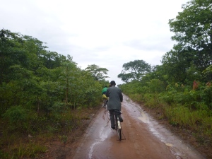 Ba Bernardi talks on his cell phone as we bike, post-rain-storm, to the tarmac road to catch transport to get goats.